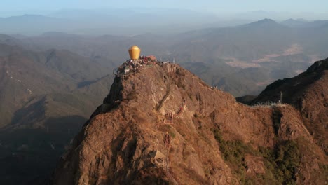 rise up over the top of the mountain with numerous tourists on top, with mountain ridge in background in afternoon