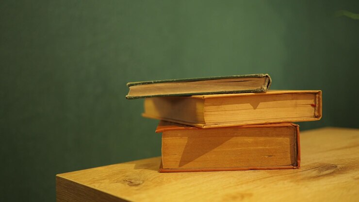 Hand Removing a Vintage Book from a Stack on a Wooden Table