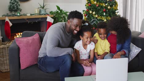 Familia-Afroamericana-Sonriente-Teniendo-Videollamadas-Y-Haciendo-Gestos,-Decoraciones-Navideñas-En-Segundo-Plano