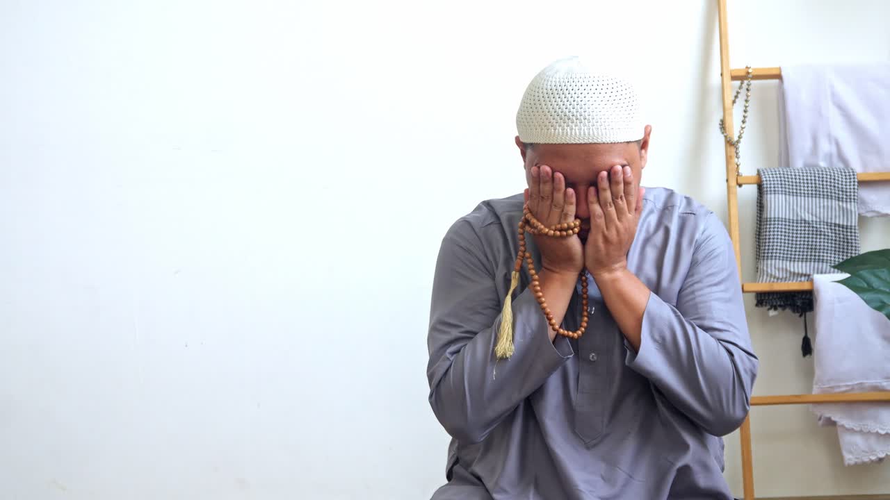 Indonesisk muslimsk mand beder med hævede hænder og reciterer dua