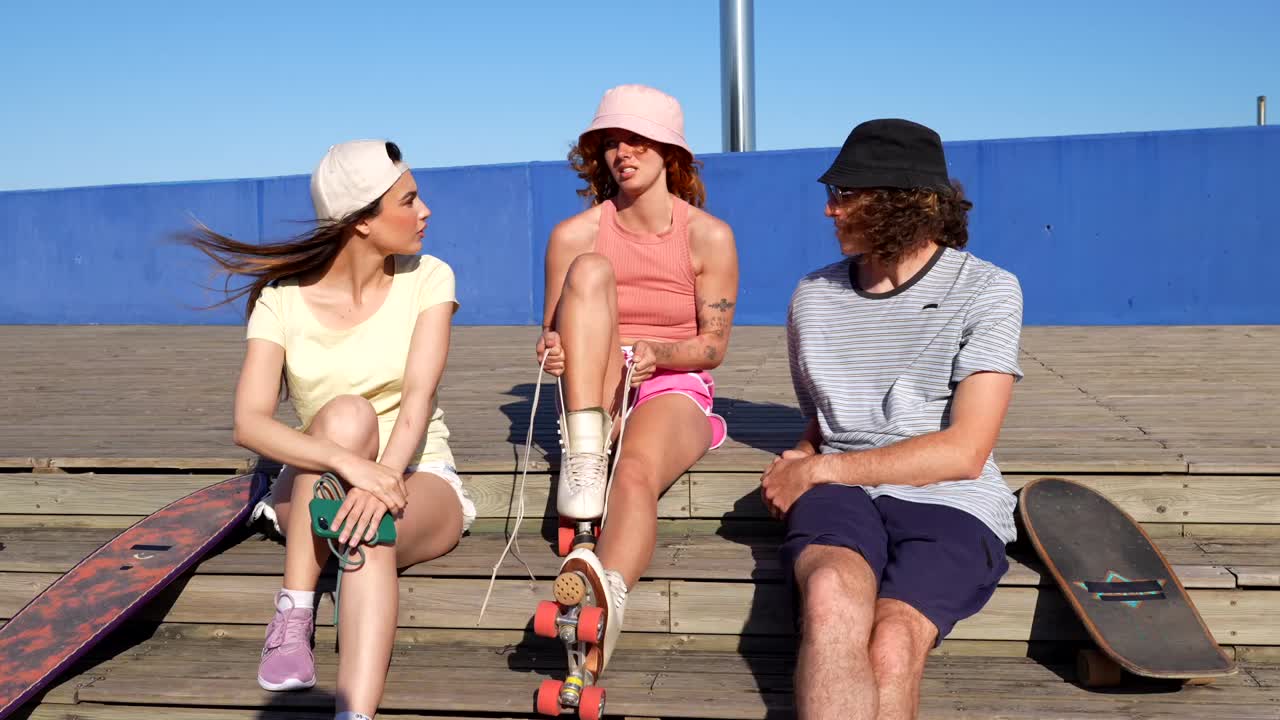 Three friends sitting on steps with skateboards and roller skates