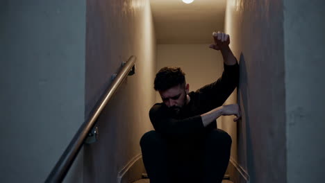 man sitting on stairs in a dark hallway