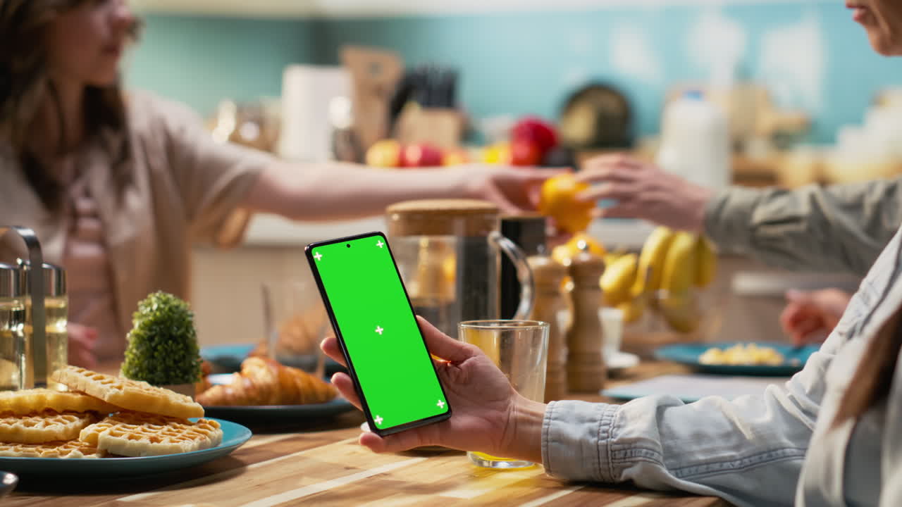 Vertical green screen phone next to mother serving breakfast with her family