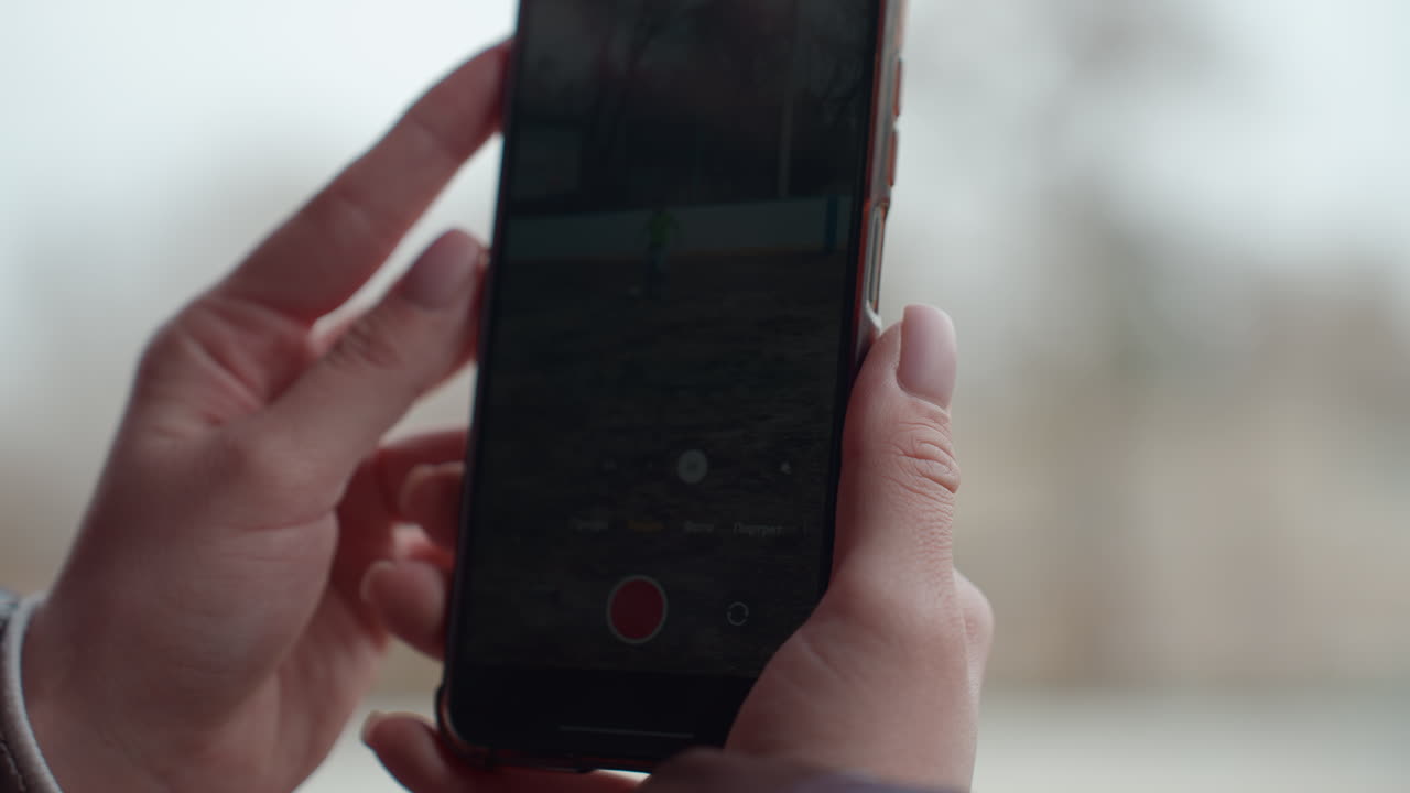 야외에서 휴대폰 화면을 조심스럽게 배열하고, 손가락으로 야외에서 미리 보기 모드를 시각화하며, 부드럽고 은은한 조명 조건 아래에서 야외의 휴대폰 화면 프레임을 창의적으로 배열해요.