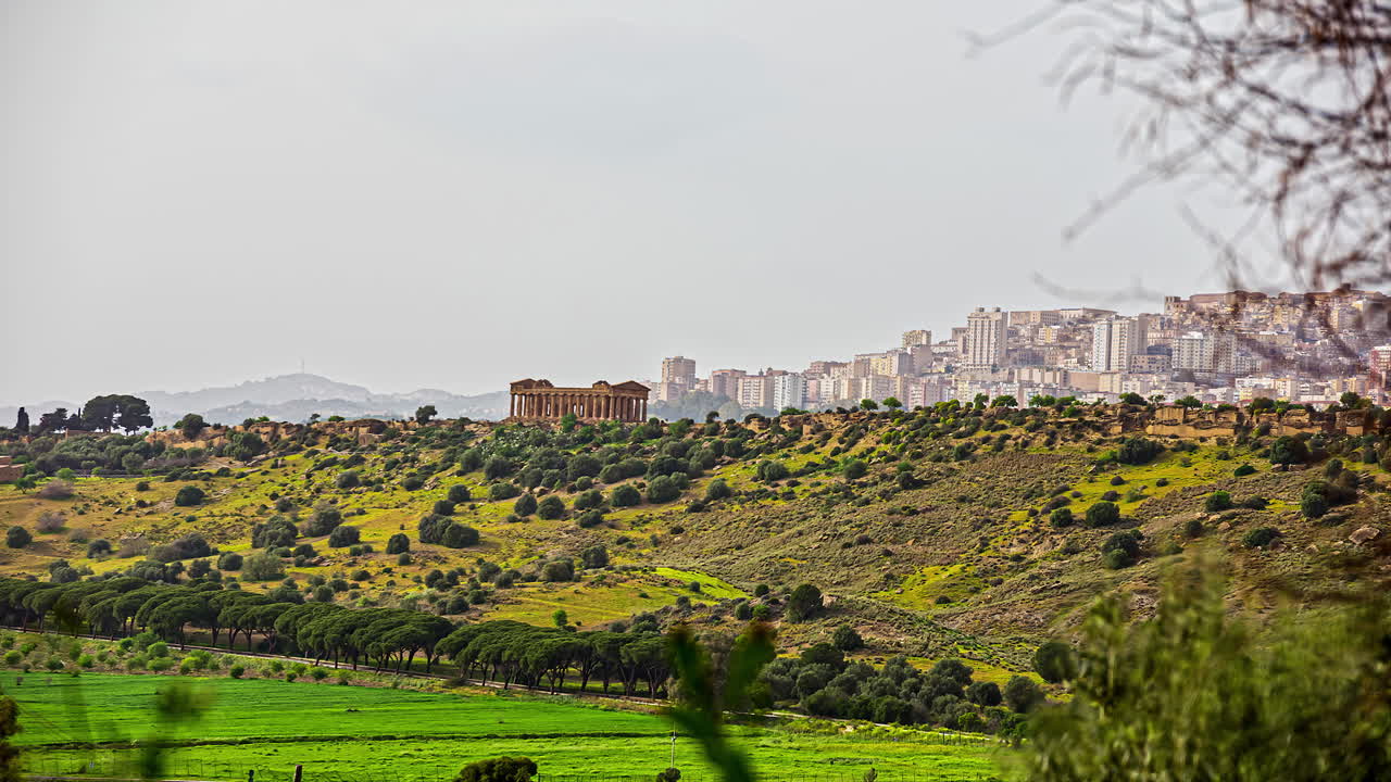toma estática del templo de segesta desde un sitio lejano con arbustos y paisaje verde en la distancia