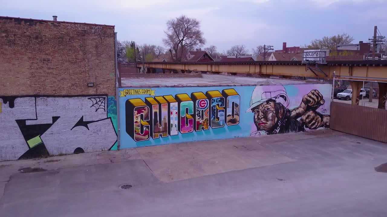 Et luftfoto over et skilt fra sentrum av Chicago malt på en vegg mens et El-tog passerer
