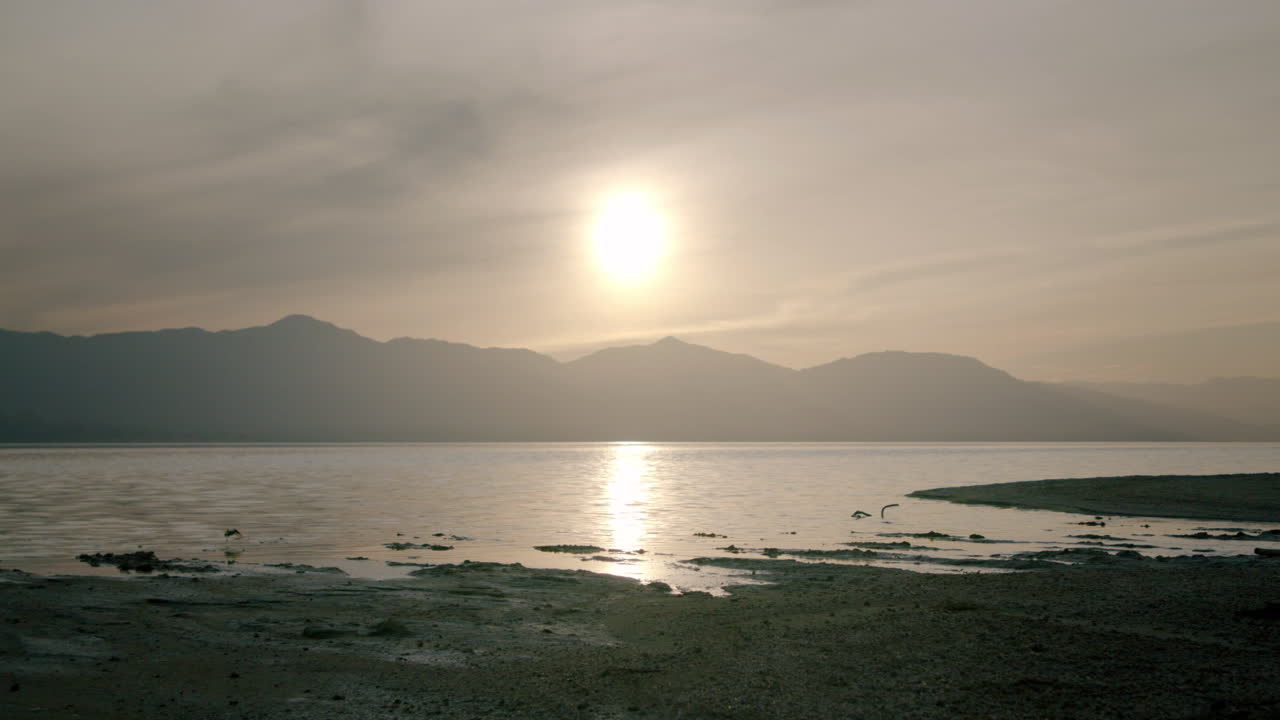 Serene Sunset Over a Calm Lake Surrounded by Mountains