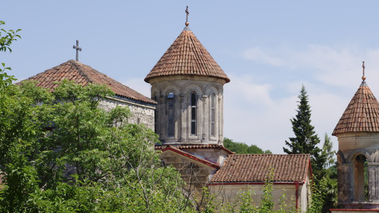 башни монастырской церкви моцамета, возвышающиеся над лиственным лесом, грузия