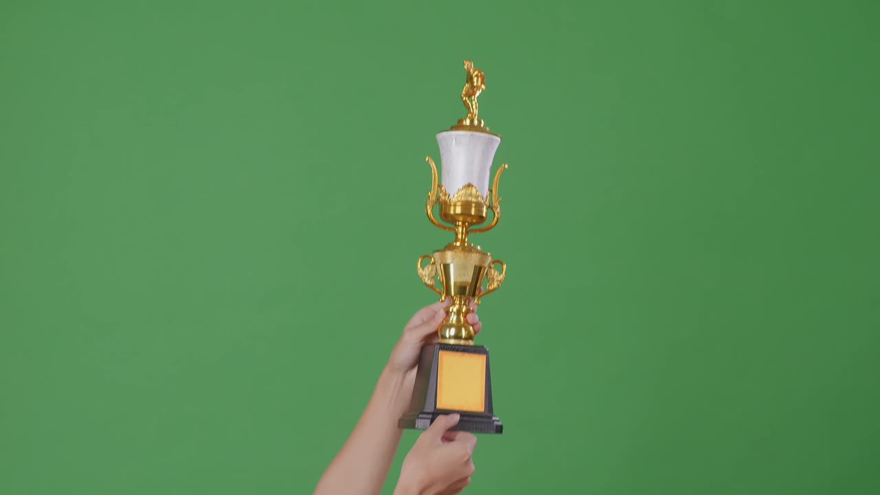 mano sosteniendo un trofeo dorado en la pantalla verde