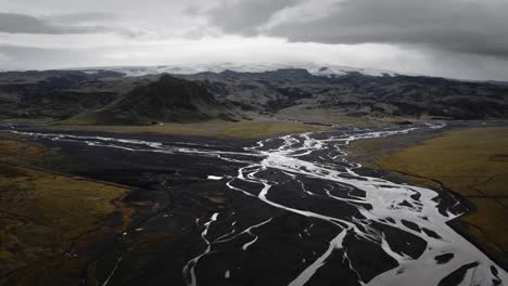 cinematic aerial glacial rivers flowing through black volcanic scenery, iceland landscape