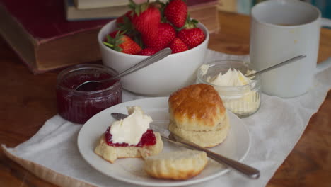 cornish scones cream and jam with a bowl of strawberries