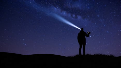 person shining flashlight into a starry night sky