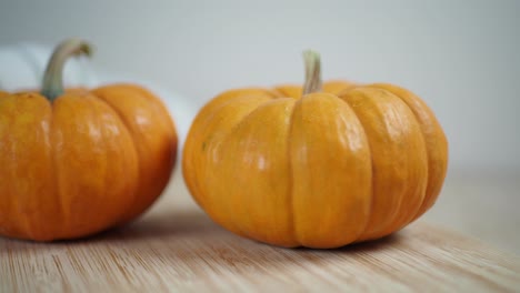 two orange pumpkins on a wooden surface