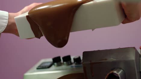 trabajador vertiendo chocolate derretido en la máquina de mezclar