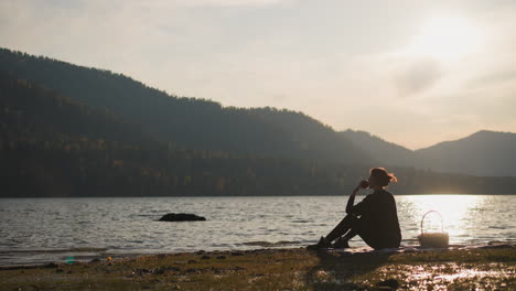 woman enjoying a picnic by a lake at sunset