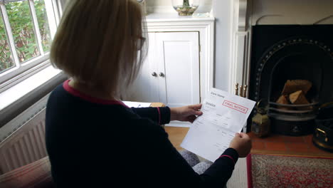 an unrecognizable senior woman worried about debts opening a debt letter