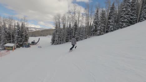 Hombre-Haciendo-Snowboard-Por-La-Ladera-De-Una-Montaña