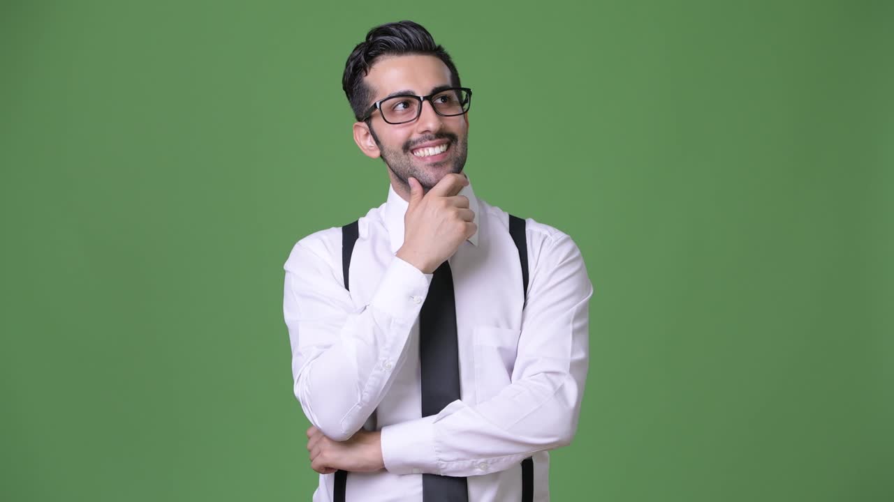 joven empresario persa barbudo y guapo contra un fondo verde