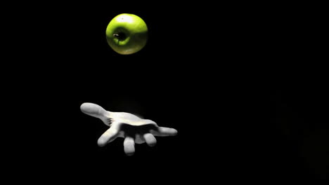 mano lanzando una manzana verde
