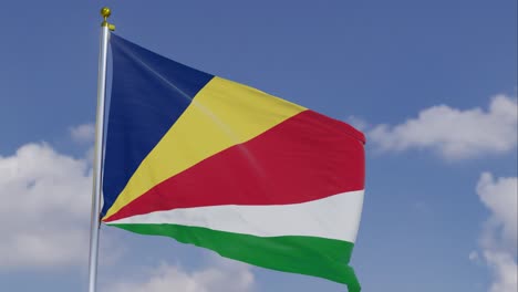 Flag-Of-Seychelles-Moving-In-The-Wind-With-A-Clear-Blue-Sky-In-The-Background,-Clouds-Slowly-Moving,-Flagpole,-Slow-Motion