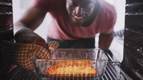 Blick-Aus-Dem-Inneren-Des-Ofens,-Während-Ein-Mann-Im-Ofen-Gebackenen-Lachs-Kocht