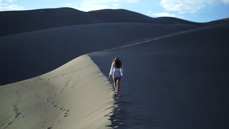 impresionante cinematográfica mujer actriz modelo traje de vaquera caminando en la cima de la cresta de colorado las grandes dunas de arena parque nacional alegría paisaje pintoresco de montaña hora de oro puesta de sol aventura montañas rocosas