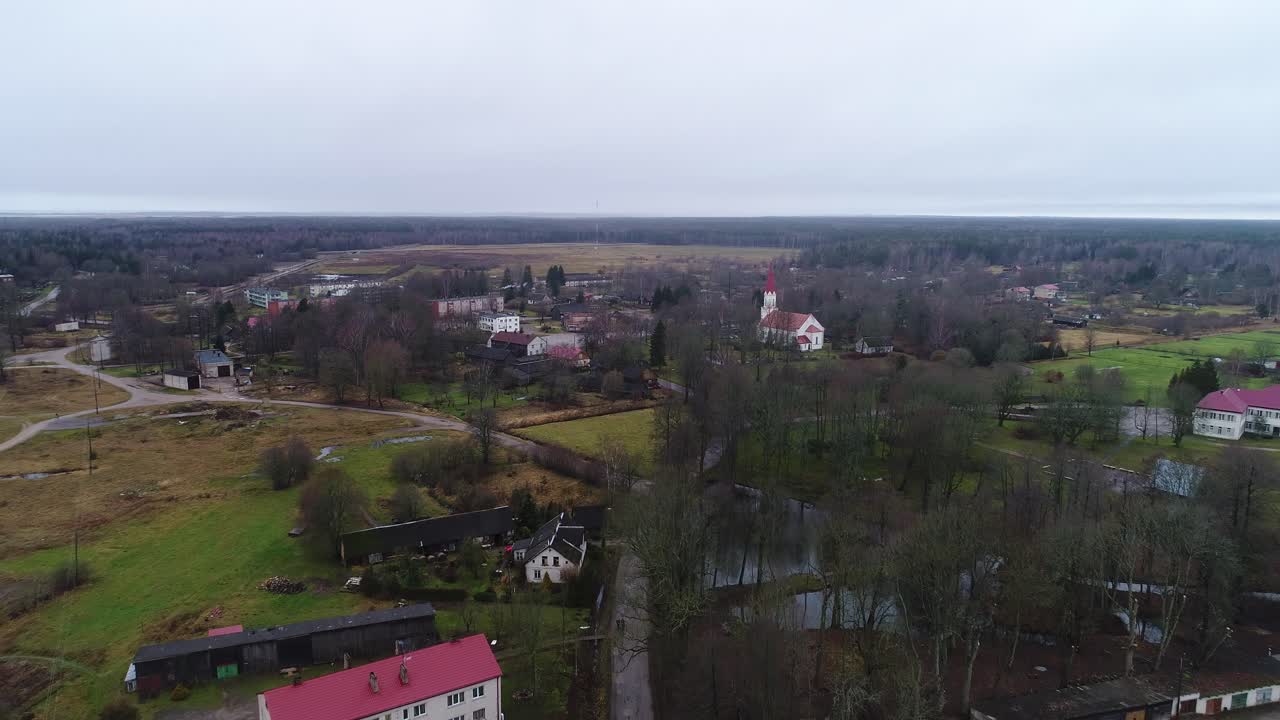 Moody aerial establishing shot, Rucava fields, church in overcast fall Latvia