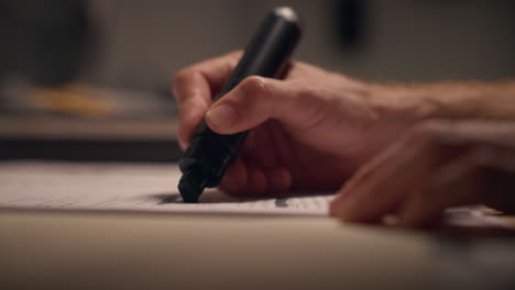 hand using black marker to hide or censor information and text from report. secret or classified document is sanitized by agent. conspiracy or military. government office important intelligence.