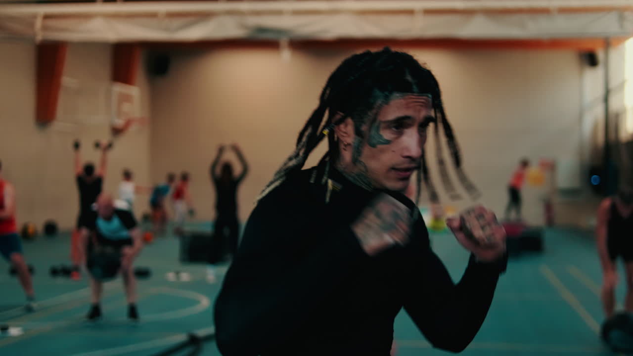 Uomo con dreadlocks e tatuaggi sul viso che fa boxe in palestra