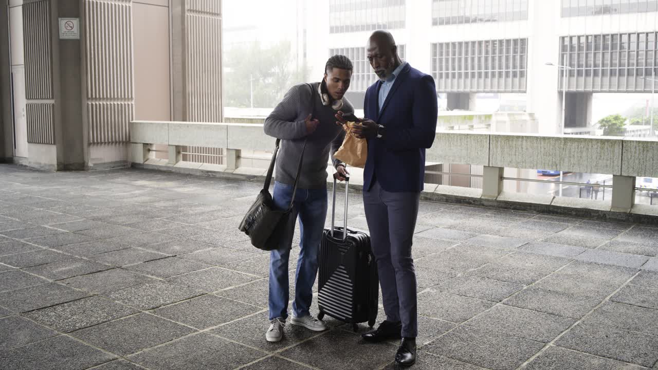After smartphone prompt Diverse men consulting phones and confirming route with suitcase on walkway