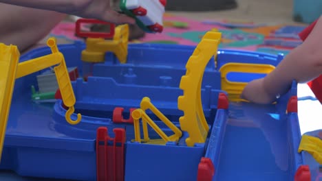 view of children playing with water toy set with one draining water from small plastic toy boat