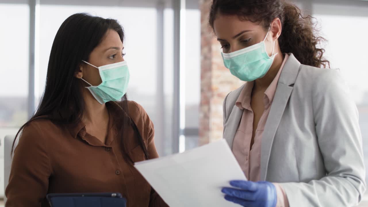 Handheld video of businesswoman reviewing sales figures with coworker