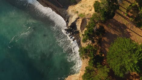 Overhead-drone-shot-of-waves-rolling-into-California's-coastline