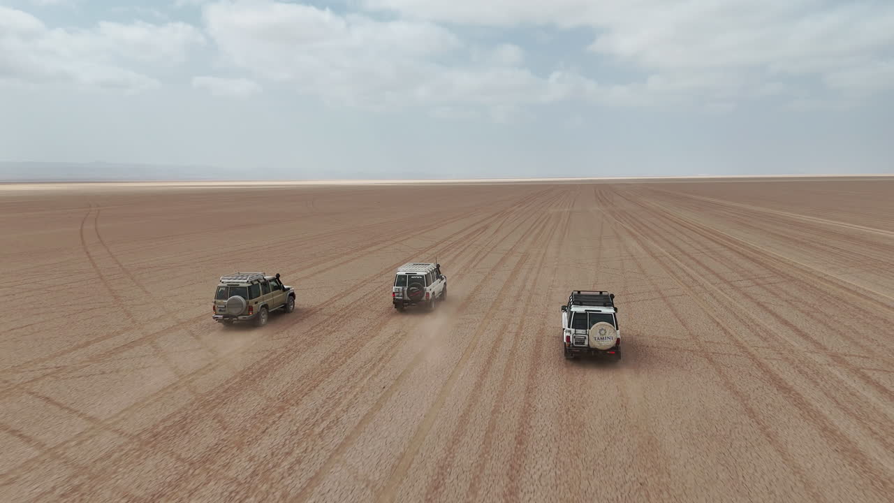 Ripresa con drone di un veicolo che attraversa un terreno desertico arido con un ampio paesaggio e texture naturali. Gibuti, Africa.