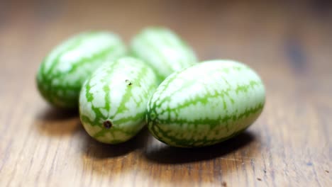 raw fresh tiny green mexican cucamelon on wooden kitchen surface selective focus left dolly closeup