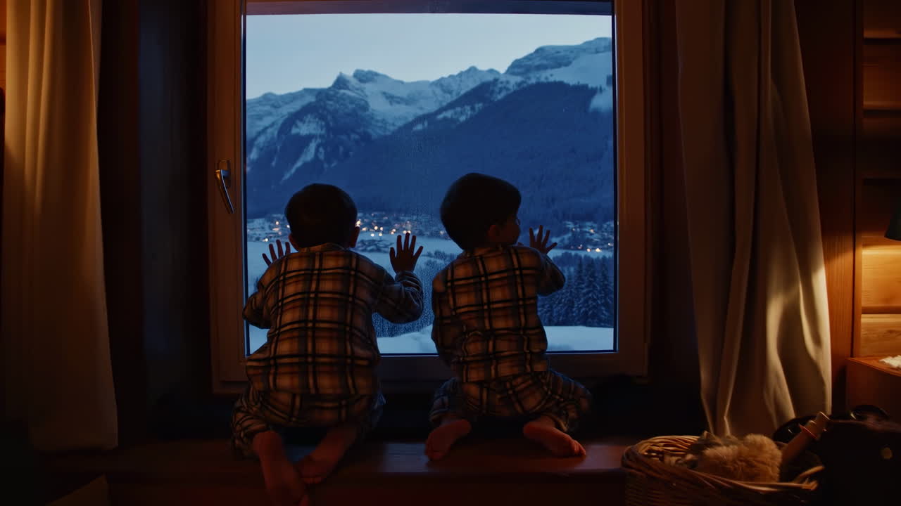 Two Boys Watching Snowy Mountain Village Lights from Window