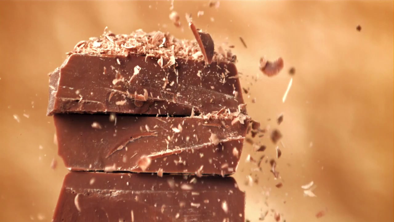 Slowmotion af chokoladespåner, der falder på stablede chokoladestykker