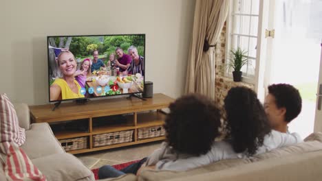 Rückansicht-Einer-Afroamerikanischen-Familie,-Die-Einen-Videoanruf-Im-Fernsehen-Führt,-Während-Sie-Zu-Hause-Auf-Der-Couch-Sitzt