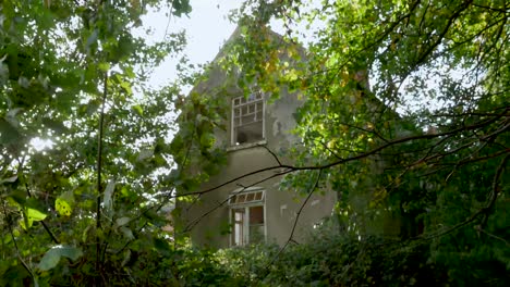 establishing shot of a creepy abandoned house with broken windows