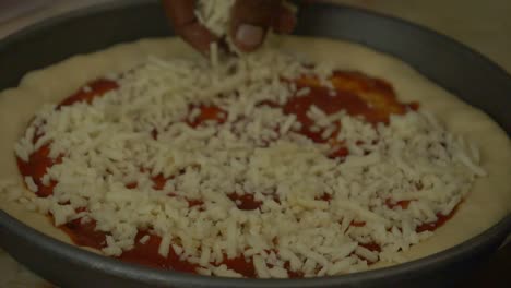 queso espolvoreado a mano sobre la base de pizza