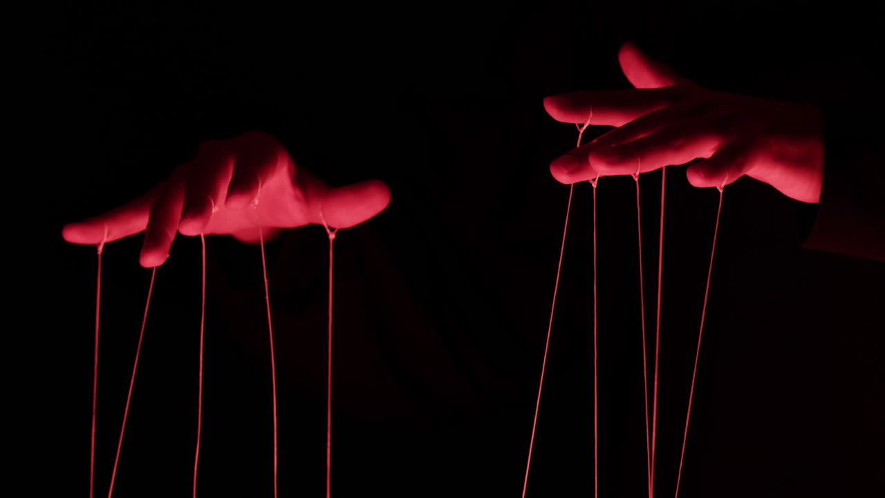 Dramatic Red Lit Hands Manipulating Puppet Strings