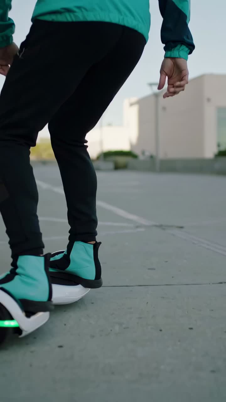 Vertical video: Stepping male onto hoverboard in plaza, in jacket and helmet, steering to glide