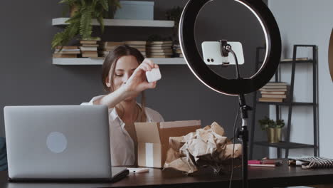 excited vlogger woman taking out of a box some technologic products and showing them to the camera