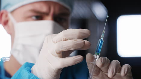 Male-healthcare-worker-flicking-barrel-of-syringe,-close-up