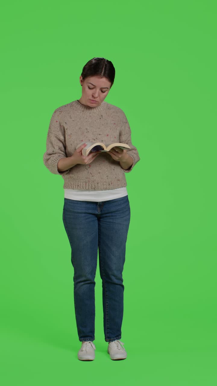 Vertical video: Front view of confident girl reading book chapter on camera