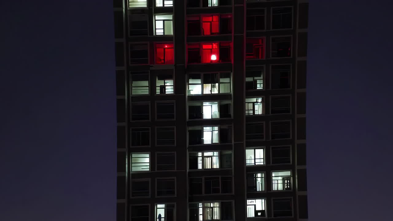 vista nocturna de un alto edificio de apartamentos con ventanas iluminadas