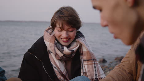 camera focuses on a teenage girl roasting marshmallows over the fire while talking to a friend who is sitting in front of her 1