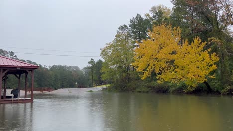 rain falling on texas lake in the fall with yellow and orange leaves on the trees near fishing boat and dock in east texas