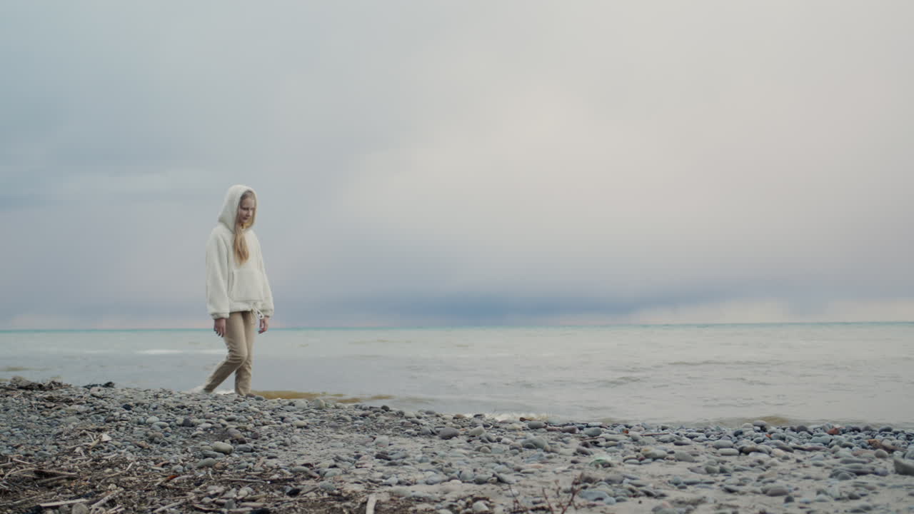 십대 소녀 가 그림 같은 호수 해안 을 따라  ⁇ 고 있다