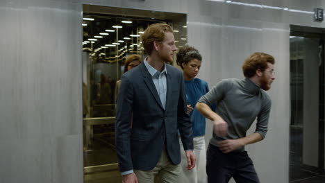 business people exiting lift in corridor